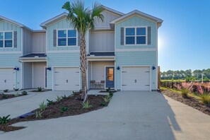 A two-story residential building with a central entrance, two garages, and a small patio area. - 2 Mi to Panama City Beach: Modern Townhome (Panama City Beach)