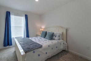 A bedroom with a bed, curtains, a nightstand, and a lamp. - 2 Mi to Panama City Beach: Modern Townhome (Panama City Beach)