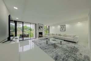 A modern living room with a glass coffee table, white sofa, and a fireplace. - Relax Poolside, Walk to Ocean! Hillsboro Beach Gem (Hillsboro Beach)