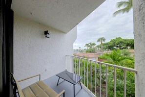 A balcony with a table and chairs, a railing, and a view of a residential area with trees and buildings. - Relax Poolside, Walk to Ocean! Hillsboro Beach Gem (Hillsboro Beach)