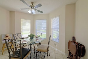 A dining area with a glass table, metal chairs, a ceiling fan, and windows with blinds. - 3 Mi to Spanish Springs! Peaceful Retreat (Lady Lake)