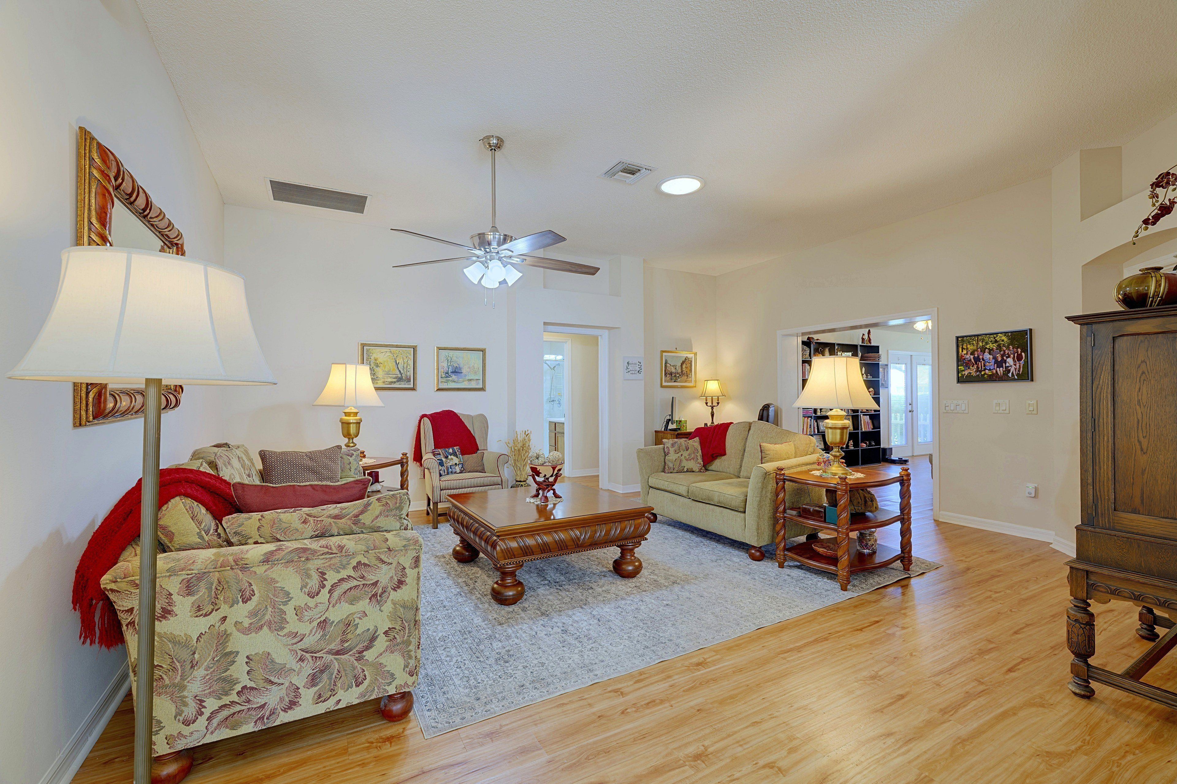 A spacious living room with a ceiling fan, a fireplace, and a large wooden cabinet.