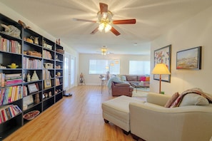 A spacious living room with a bookshelf, a ceiling fan, a sofa, and a painting on the wall. - 3 Mi to Spanish Springs! Peaceful Retreat (Lady Lake)