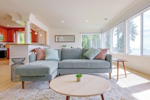 A modern living room with a sectional sofa, a round coffee table, and a view of the outdoors. - Your Oceanfront Home Away From Home in Long Beach (Long Beach)