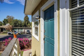 A residential house with a teal door, a visible window with blinds, and a driveway with parked cars. - Walk to Pickleball, Parks, Pubs! Cozy Dtwn Apt (Bakersfield)