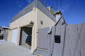 A residential garage with a closed garage door, a wooden fence, and a clear sky. - Chic Apt < 5 Mi to Sdsu! Private Patio & Views (San Diego)