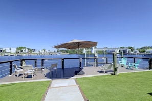 A waterfront deck with outdoor seating, a wooden walkway, and a clear view of the water. - Right on Canal! Sleek Home Near Gulf Coast Fun (Hudson)