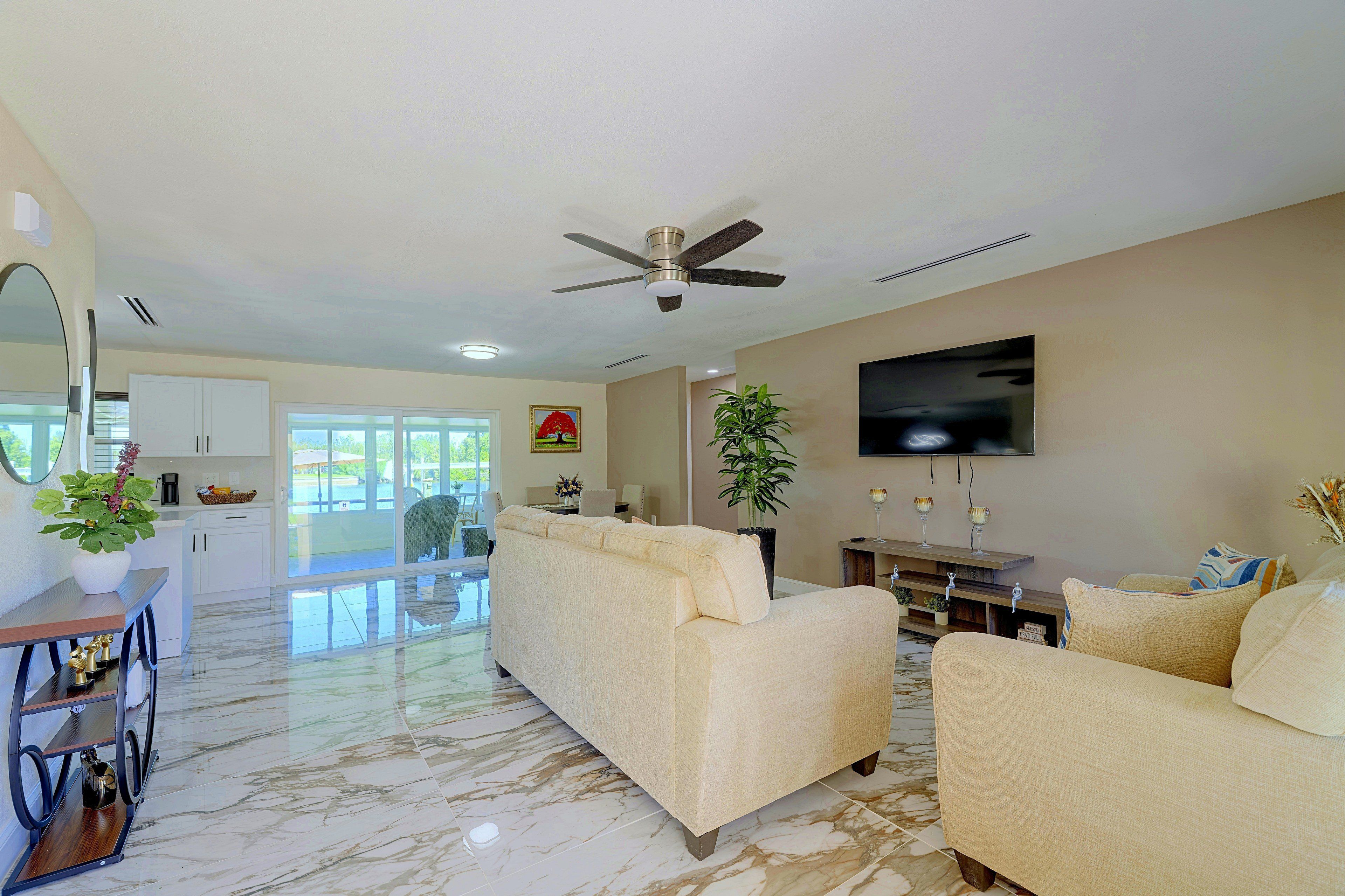 A spacious living area with a sofa, a television mounted on the wall, and a ceiling fan.