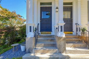 A two-story building with a symmetrical facade, a central entrance with a dark-colored door, and a set of stone steps leading to the entrance. - Victorian Condo in Providence Near Brown Uni (Providence)