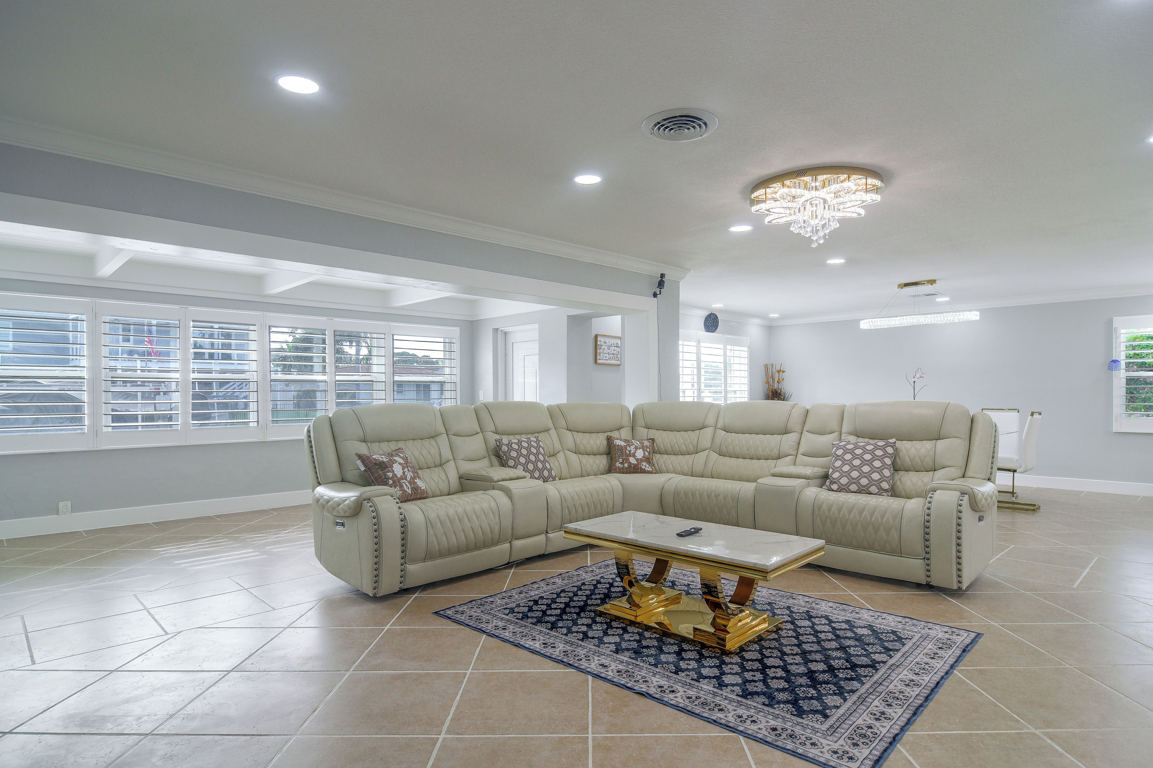 A spacious living room with a sectional sofa, a coffee table, and a chandelier.