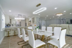 A modern kitchen with white cabinetry, a marble countertop, and a central island with bar stools. - Canal-front Retreat w/ Dock! 5 Mi to Dtwn St Pete (St. Petersburg)