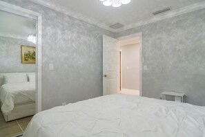A bedroom with a bed, a door, and a small bedside table. - Canal-front Retreat w/ Dock! 5 Mi to Dtwn St Pete (St. Petersburg)