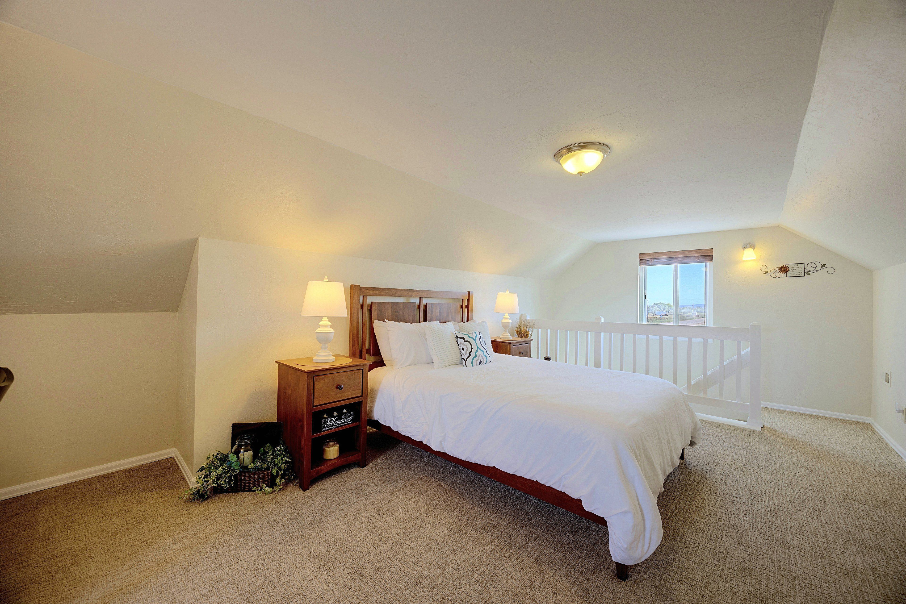 A bedroom with a single bed, nightstands, a dresser, a window with a view, and a ceiling light.