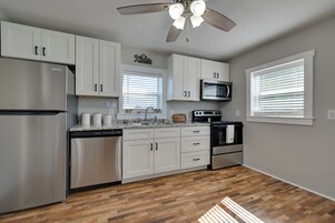 Una cocina moderna con armarios blancos, un refrigerador de acero inoxidable, un microondas y una estufa.