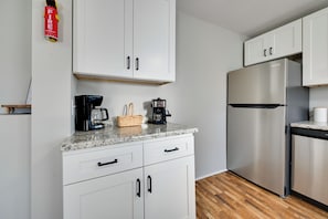 Eine moderne Küche mit weißen Schränken, einem Edelstahl-Kühlschrank, einer Kaffeemaschine und einem Korb auf der Arbeitsfläche.