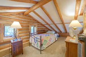 Un dormitorio de cabaña con una cama, dos lámparas de noche, un aparador y una ventana.