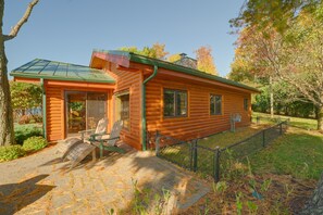 A log cabin with a porch, a chair, and a small table. - Waterfront Lake Charlevoix Cabin 8 Mi to Boyne Mtn (Boyne City)