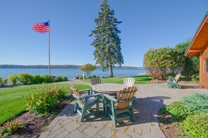 Eine Terrasse mit Tisch und Stühlen, eine Flagge und Blick auf einen See.