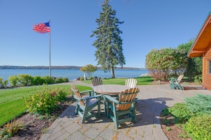 Un patio con una mesa, sillas, una bandera y vista al lago.