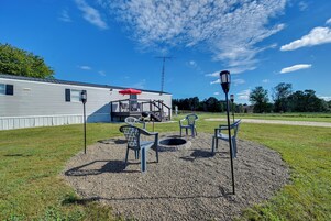 Un patio con mobiliario exterior, una chimenea y un edificio al fondo.