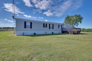 A single-story mobile home with a fenced yard, a wooden deck, and a tree. - Countryside Gem w/ Fire Pit: 14 Mi to Mammoth Cave (Brownsville)