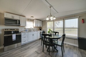 A modern kitchen with white cabinets, a built-in microwave, a stove, and a dining area with a table and chairs. - Countryside Gem w/ Fire Pit: 14 Mi to Mammoth Cave (Brownsville)