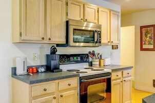 Una cocina con armarios de madera, un microondas de acero inoxidable, una cafetera y una estufa.