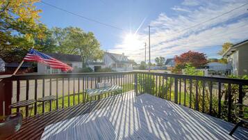 A wooden deck with a view of a residential street, a flag, and houses.