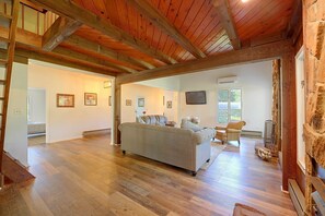 A spacious living room with hardwood floors, a grey sofa, and a television mounted on the wall. - Lake Hartwell Home w/ Quiet Patio & Lake Access (Townville)