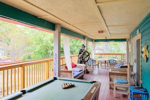 A pool table with billiard balls, a wooden bench, and a table with chairs on a wooden deck. - Water Views + Patio Brews! Middle Bass Island Home (Put-in-Bay)