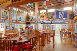 A restaurant interior with wooden furniture, a TV screen displaying sports, and various decorations including pumpkins and a flag.