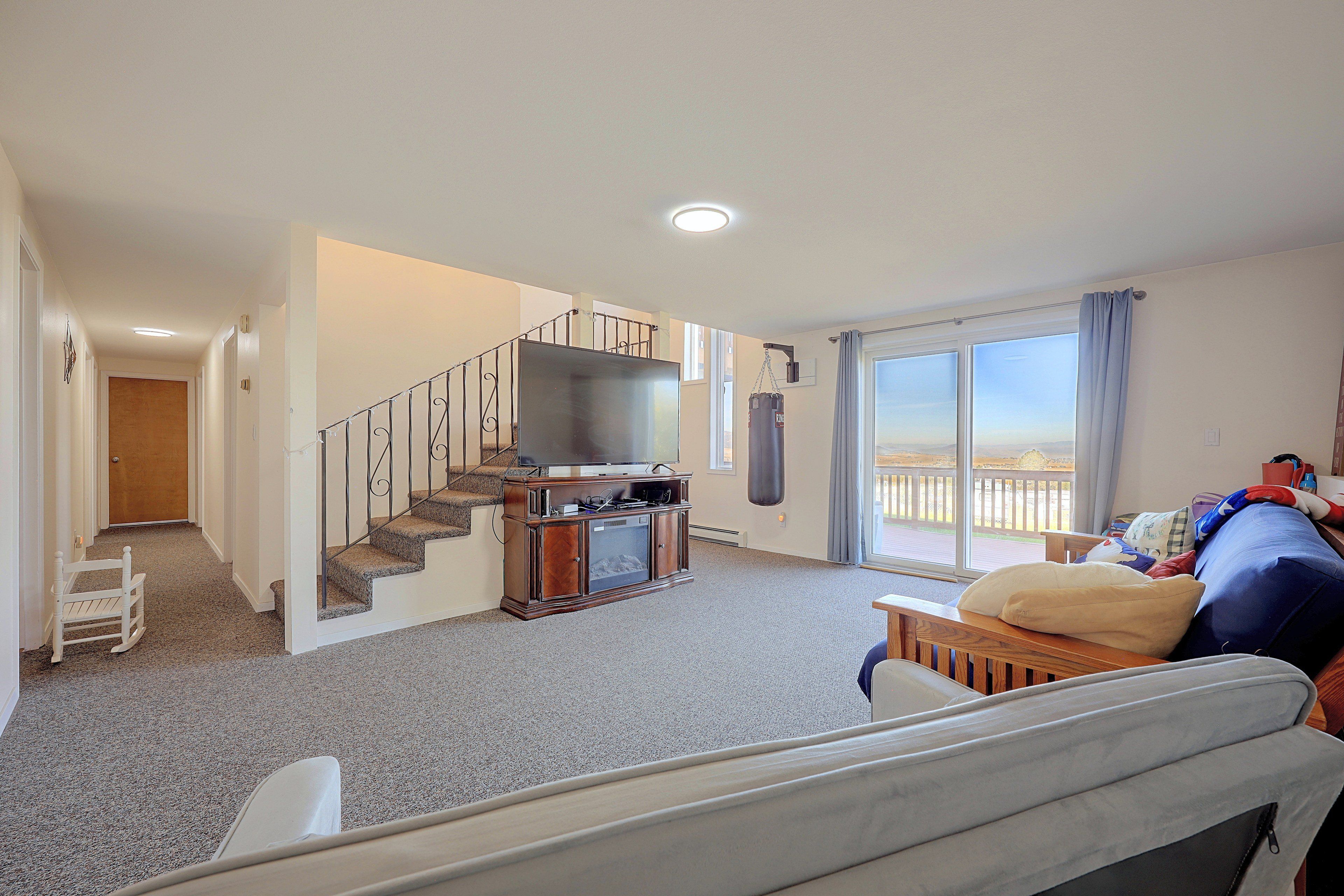 Un salon avec un escalier, un téléviseur à écran plat, un sac de frappe et un balcon avec vue.