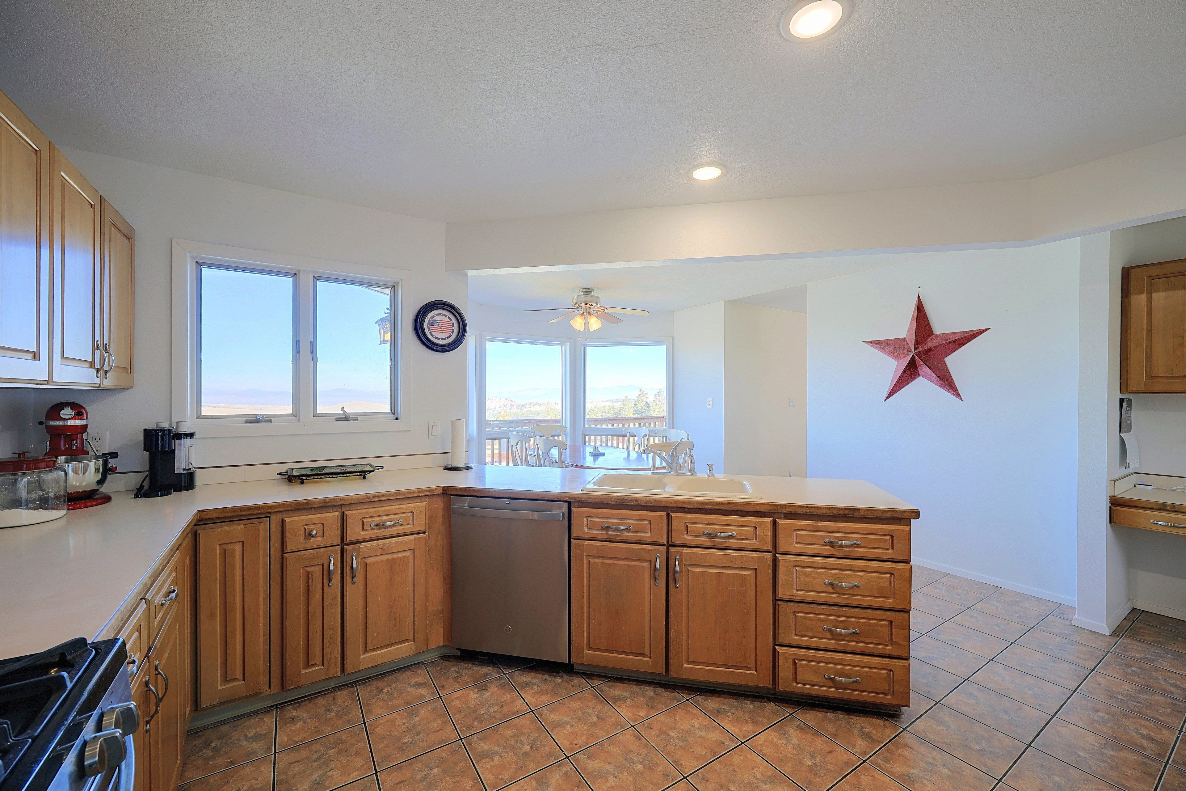 A kitchen with wooden cabinets, a dishwasher, a large island, and a red star decoration on the wall.
