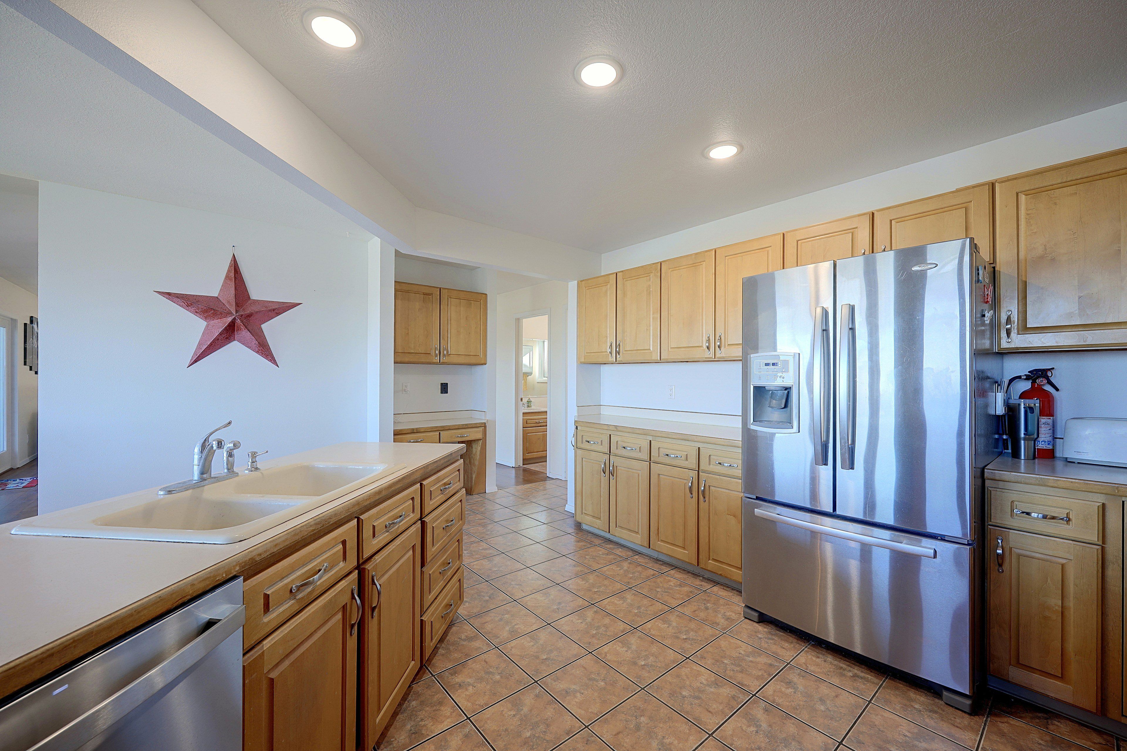 A kitchen with wooden cabinets, stainless steel appliances, and a tiled floor.