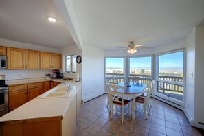 A kitchen with wooden cabinets, a white countertop, and a dining area with a table and chairs. - Helena Valley Home w/ Mtn Views & Acre (Clancy)