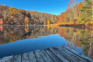 A calm lake with a wooden dock extending into the water, surrounded by autumn-colored trees. - Hocking Hills Area Retreat: Relax & Explore! (Rockbridge)