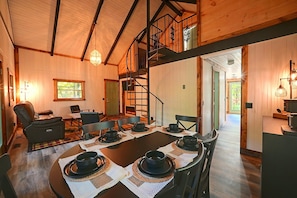A cozy interior with a dining area, a staircase, and a view of the outdoors. - Hocking Hills Area Retreat: Relax & Explore! (Rockbridge)