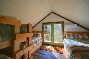 A cozy attic bedroom with wooden bunk beds, a large window, and a ceiling fan. - Hocking Hills Area Retreat: Relax & Explore! (Rockbridge)