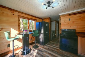 Ein Interieur einer Hütte zeigt einen Essbereich, Barhocker, einen Kühlschrank und einen Herd.