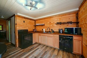 A kitchen with wooden walls, a black stove, a sink, a microwave, and a dishwasher. - 7 Mi to Hocking Hills! Family & Dog-friendly Haven (Rockbridge)