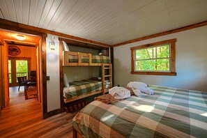A room with a bunk bed, a window with a view of trees, and a door leading to a balcony. - Hocking Hills Area Retreat: Relax & Explore! (Rockbridge)