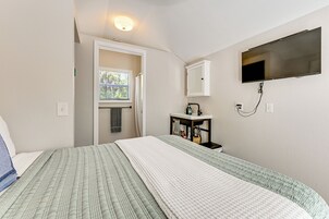 Un dormitorio con cama, ventana, lavamanos y televisión.