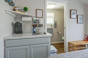Cocina compacta con cafetera, lavamanos y una pequeña encimera.
