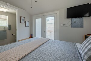 Un dormitorio con cama, televisor montado, ventana con persianas y termostato en la pared.