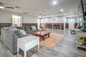 A modern living room with a sectional sofa, a coffee table, and a small white table. There is a fireplace with a mantel and a clock on the wall. - Riverside Retreat -horse Creel Retreat Arcadia (Fort Ogden)