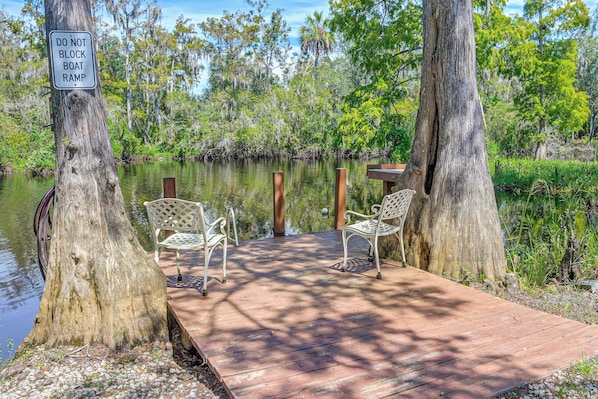 A wooden dock with two white metal chairs, surrounded by trees and a body of water. - Riverside Retreat -horse Creel Retreat Arcadia (Fort Ogden)