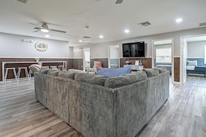 A modern living room with a large sectional sofa, a flat-screen TV, and a wooden floor. - Riverside Retreat -horse Creel Retreat Arcadia (Fort Ogden)
