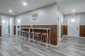 A lobby area with a reception desk, bar stools, and a clock on the wall. - Riverside Retreat -horse Creel Retreat Arcadia (Fort Ogden)