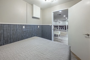 A hotel room with a bed, a door leading to a bathroom, and a view of a bar area. - Riverside Retreat -horse Creel Retreat Arcadia (Fort Ogden)