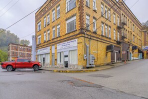 A multi-story yellow brick building with a red pickup truck parked in front. - Sunny Welch Apt: Walk to Riverfront Park! (Welch)
